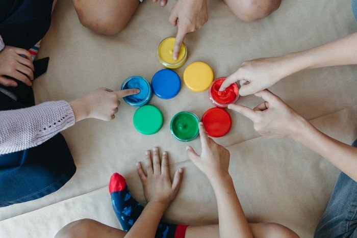 Children reaching for colorful paints together